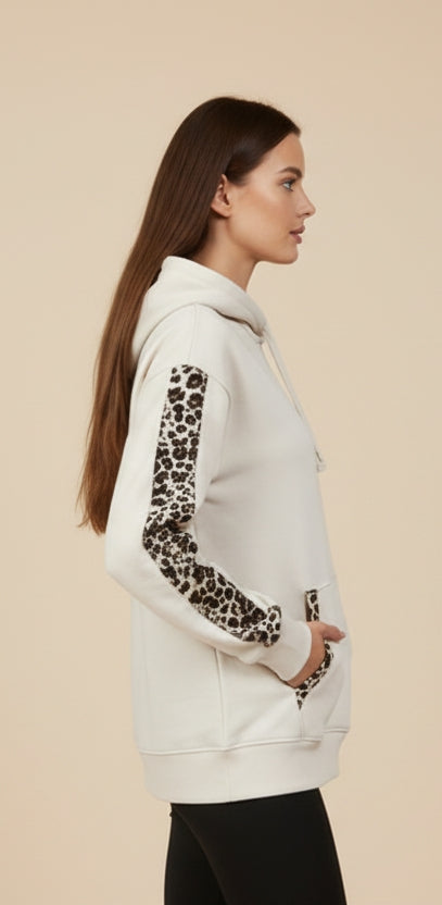 Modella indossa FELPA PUMA DONNA 688084 BEIGE con mani in tasca in vista laterale per mostrare dettagli animalier su maniche e cuciture nelle tasche a marsupio 